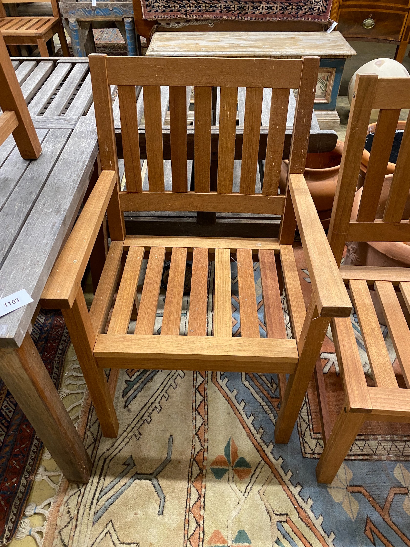 A weathered teak square garden table, width 80cm, height 73cm together with two teak elbow chairs